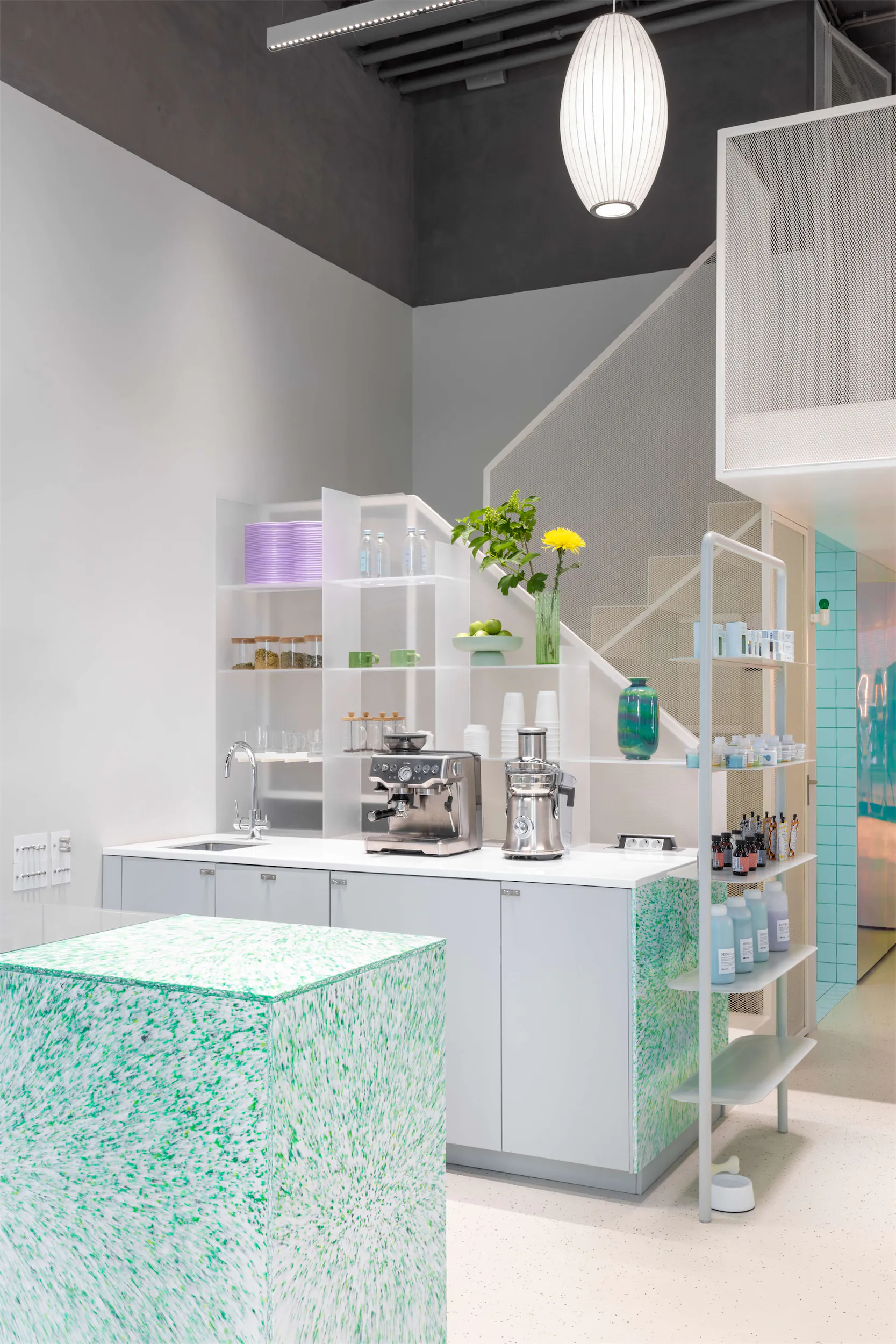 Modern interior with white cabinets, green marble countertop, and hanging light fixture.