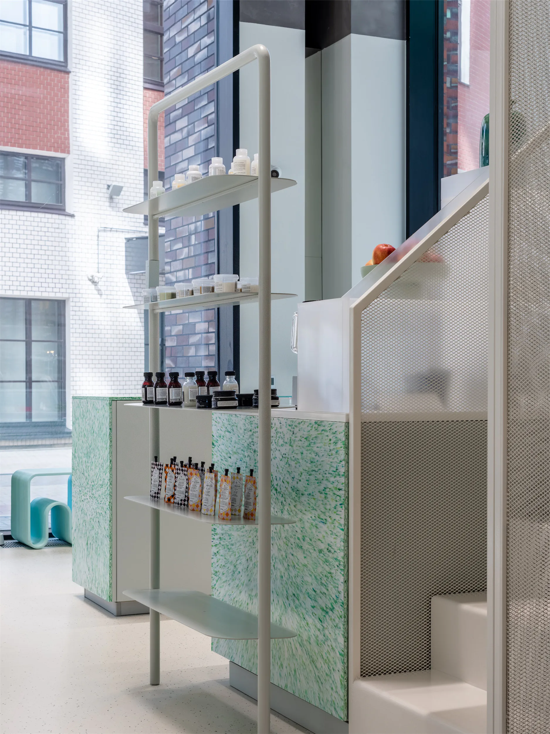 Современный белый стеллаж с основанием из зелёного мрамора и белой лестницей у окна.