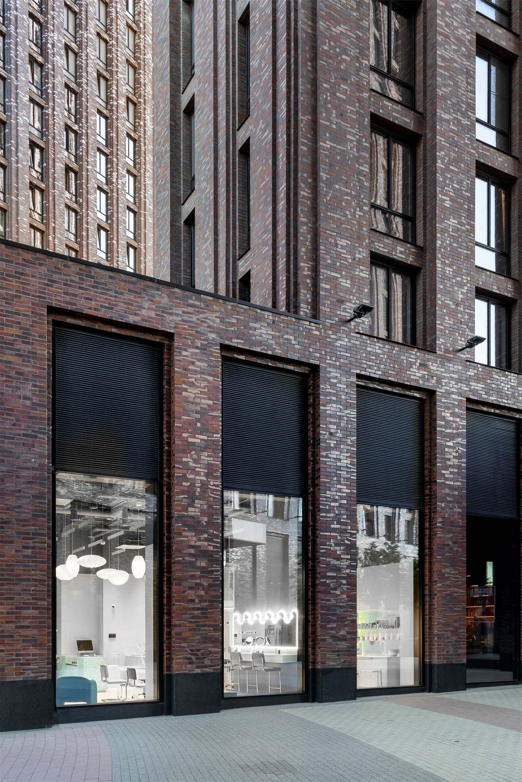 Современный фасад здания с большими окнами и кирпичной кладкой.