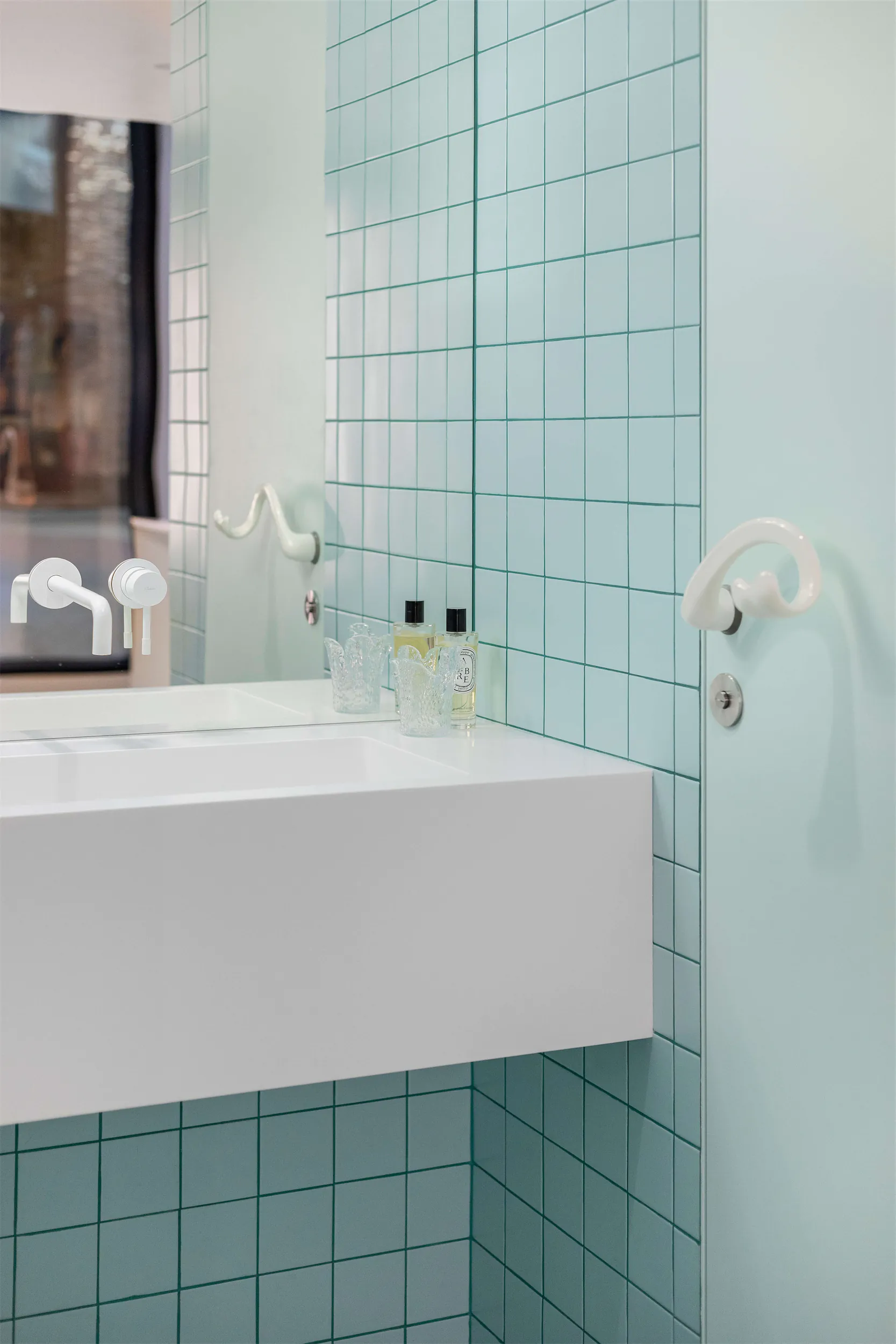 Белая раковина на фоне светло-голубой плиточной стены с зеркалом.