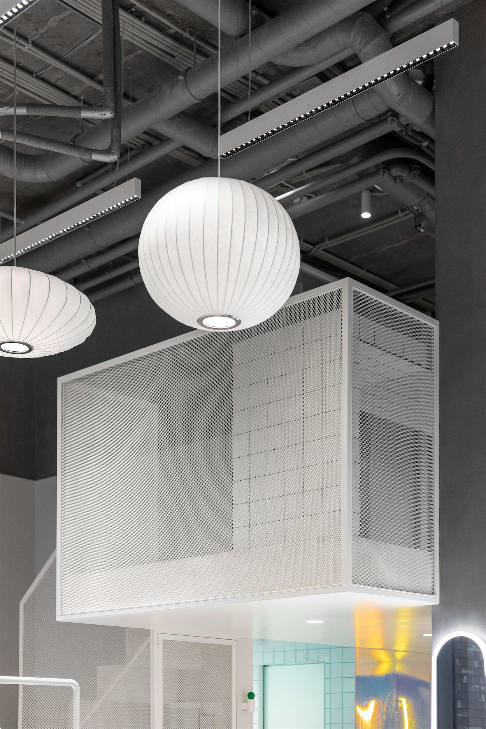 Современная белая комната с большим подвесным светильником в форме шара.