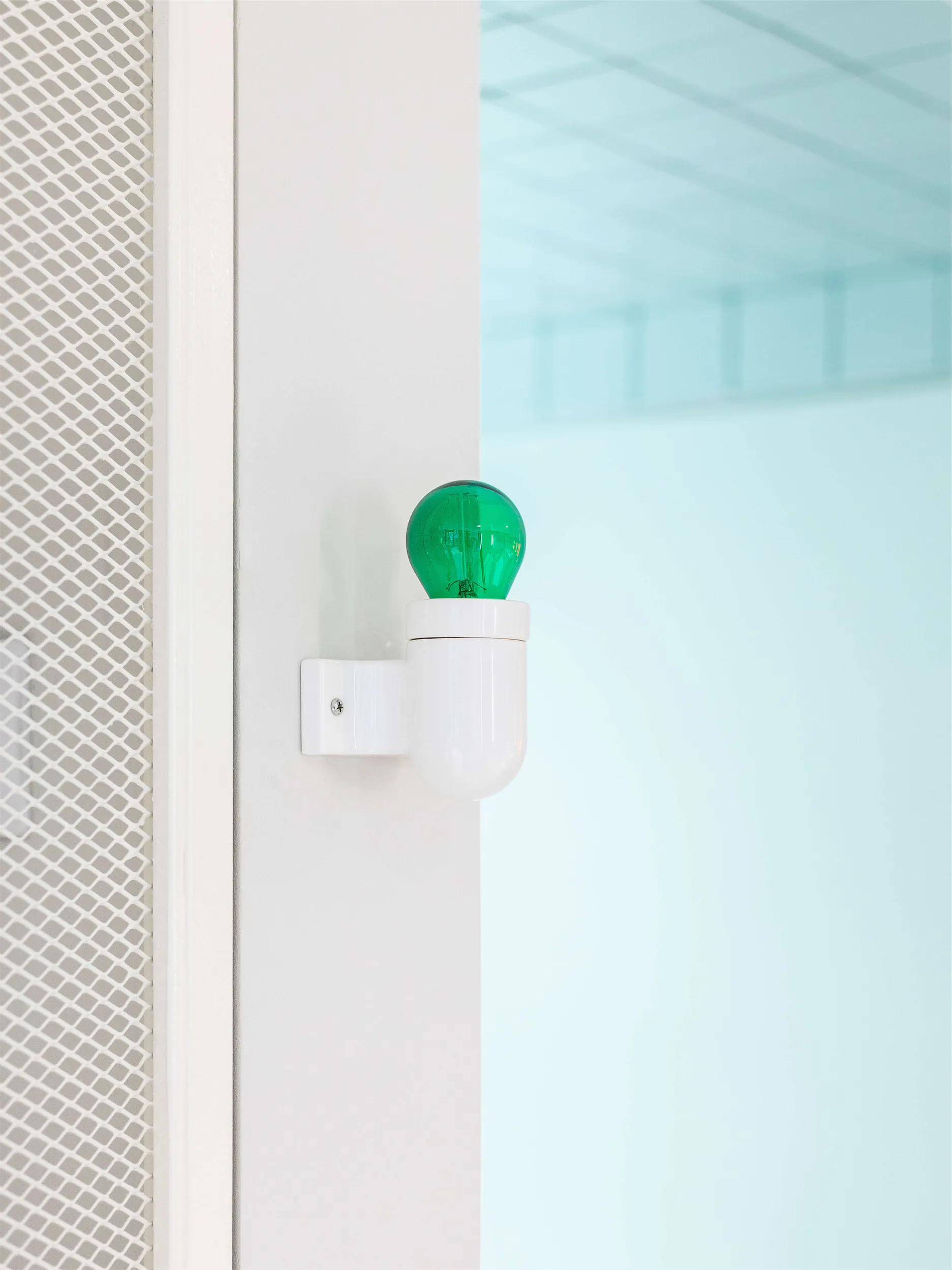 Белая стена с зелёной лампочкой.