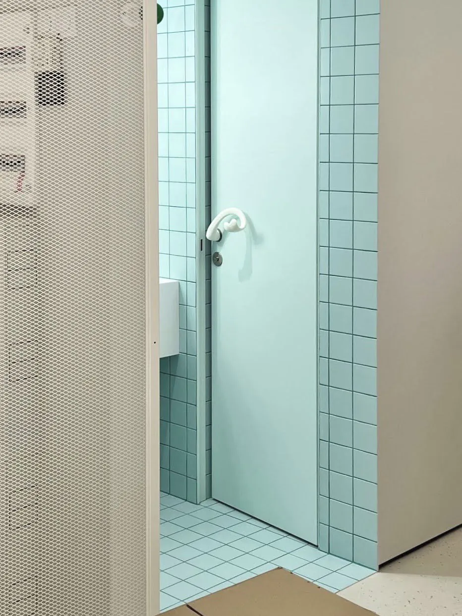 Дверь с ручкой на фоне стены с белой и голубой плиткой.