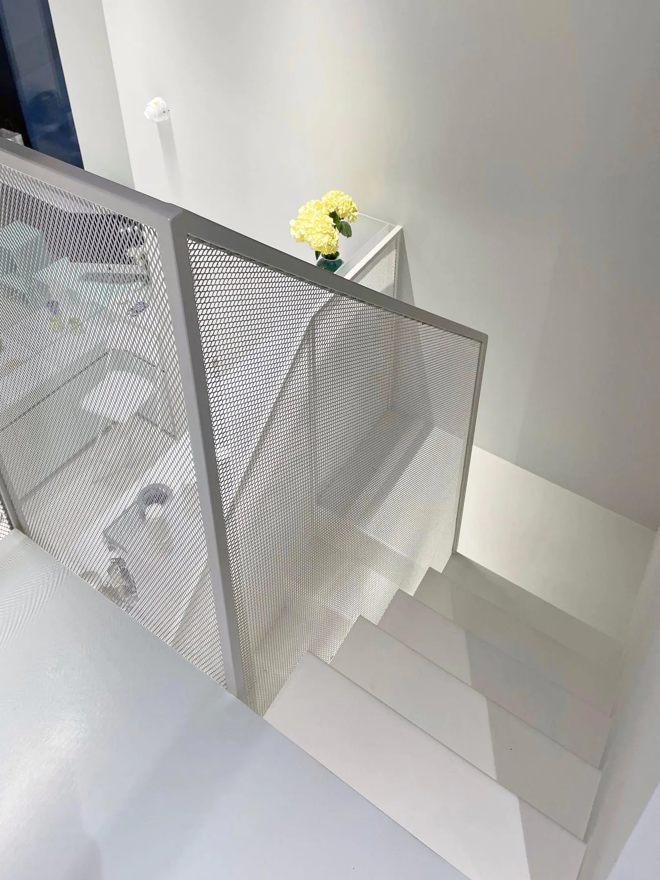 Белая лестница с металлическими перилами и жёлтым цветком.