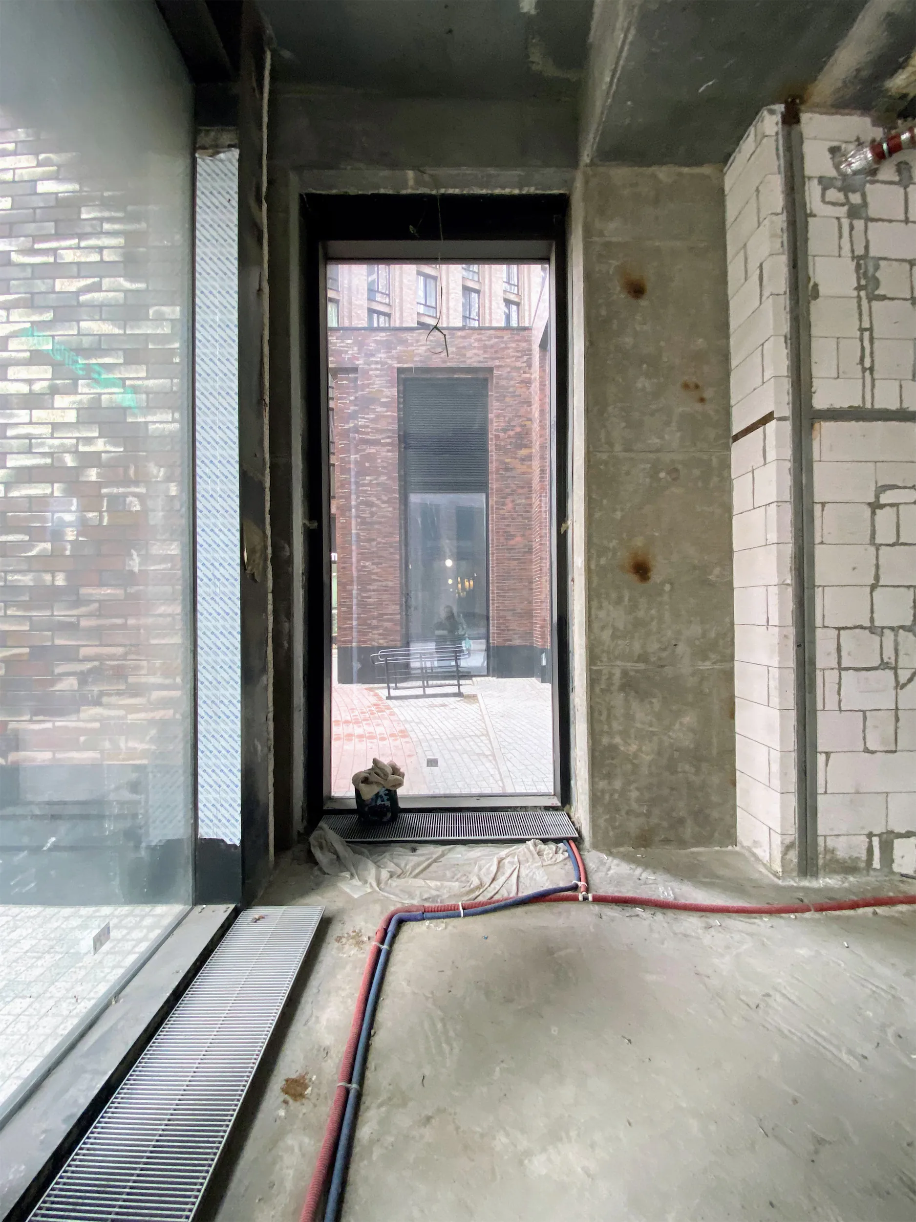 Дверной проём с красным, синим и чёрным электрическими кабелями на полу.