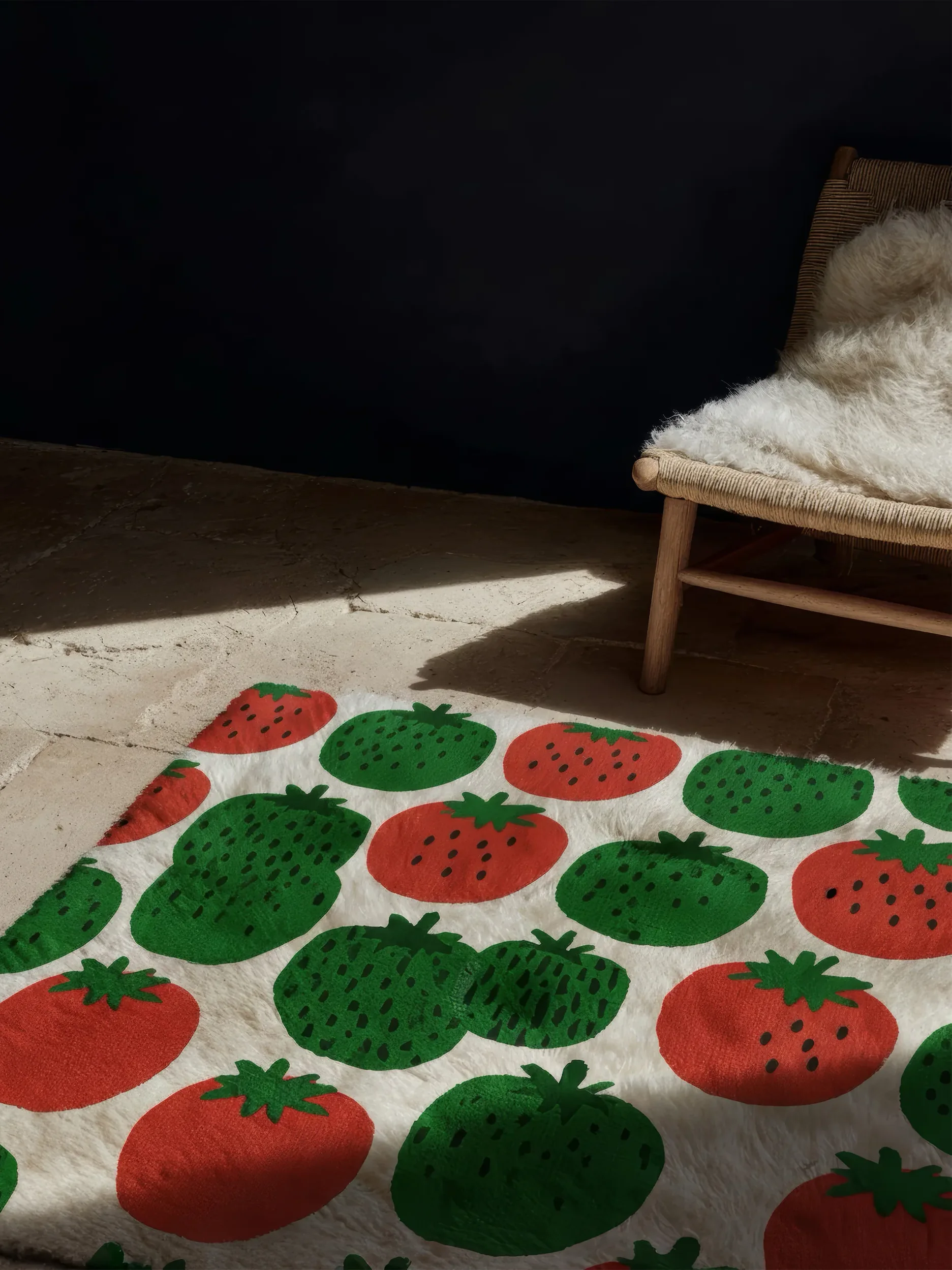 Ковёр с рисунком клубники на полу рядом со стулом с белой подушкой.