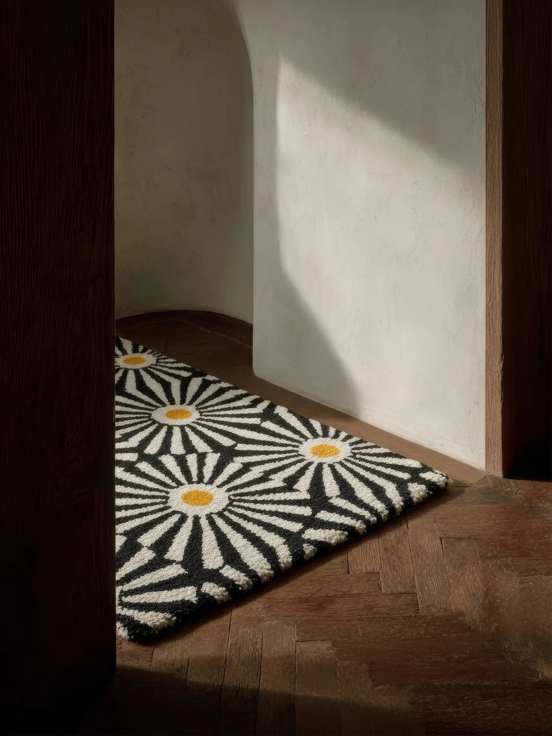 Чёрно-белый ковёр с жёлтым цветочным орнаментом на тёмном деревянном полу.