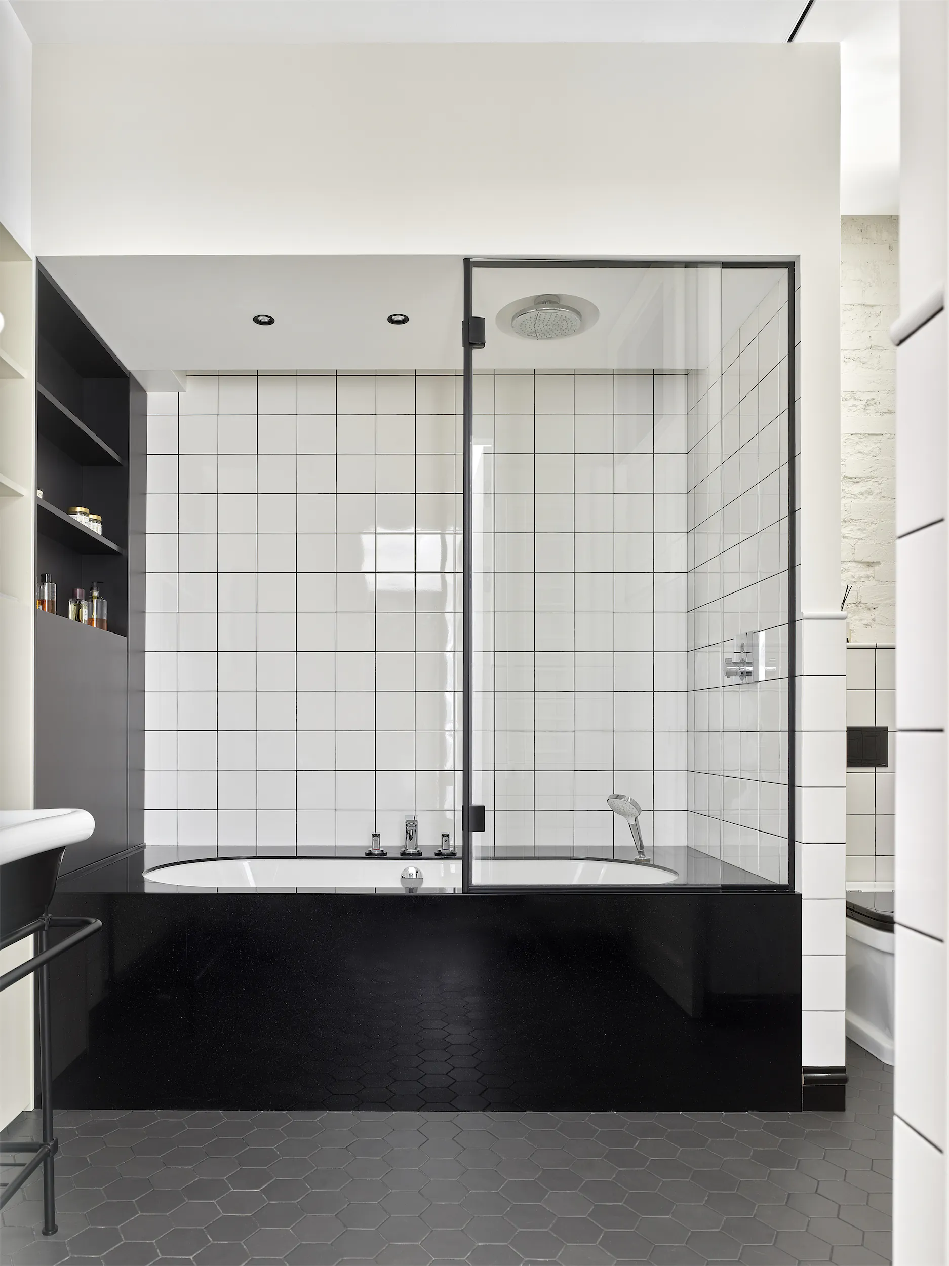 Минималистичная ванная с ванной и белой плиткой в чёрно-белой гамме.