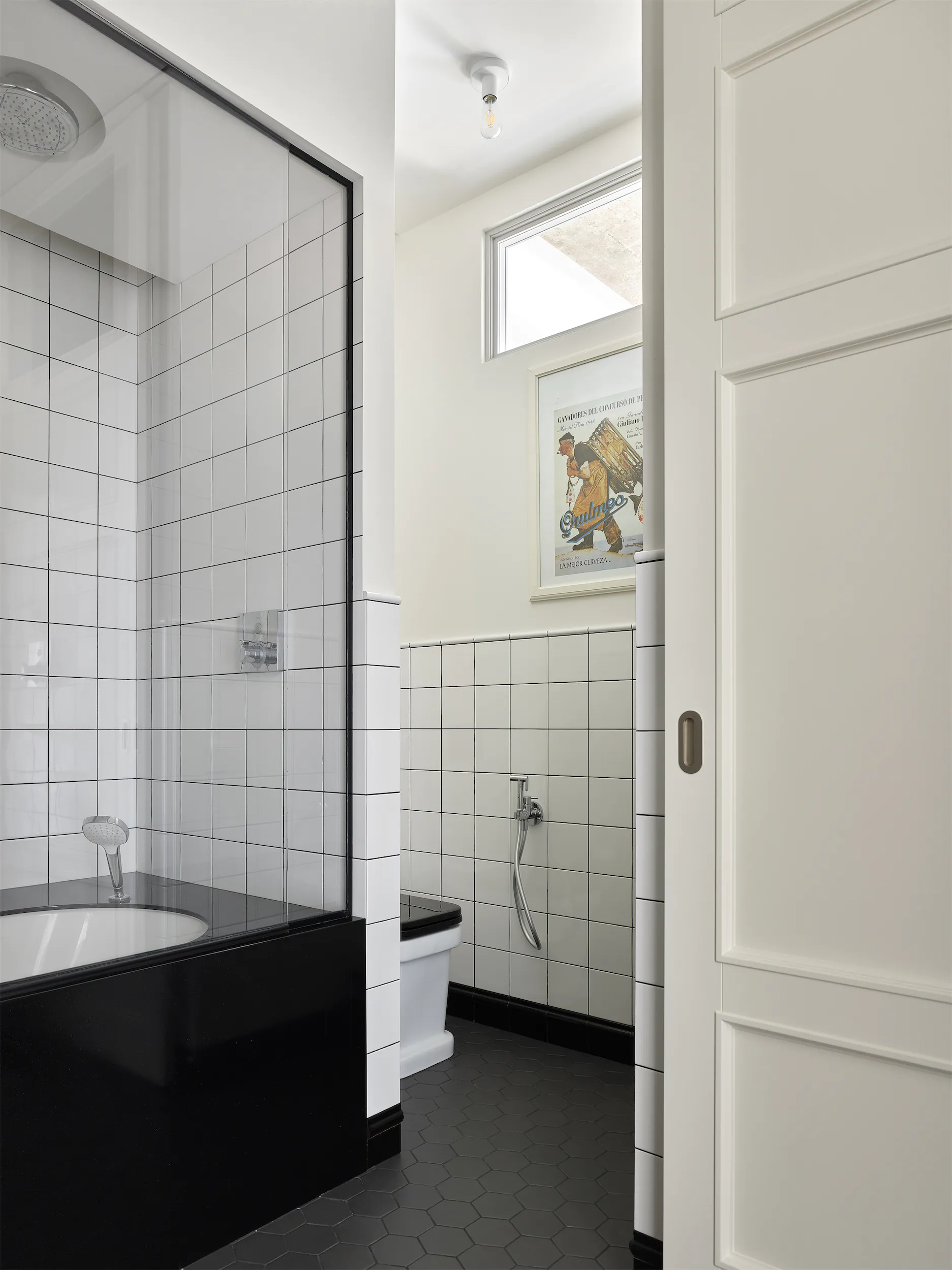 Белая ванная с чёрной окантовкой, белой ванной и белой дверью с серебристой ручкой.