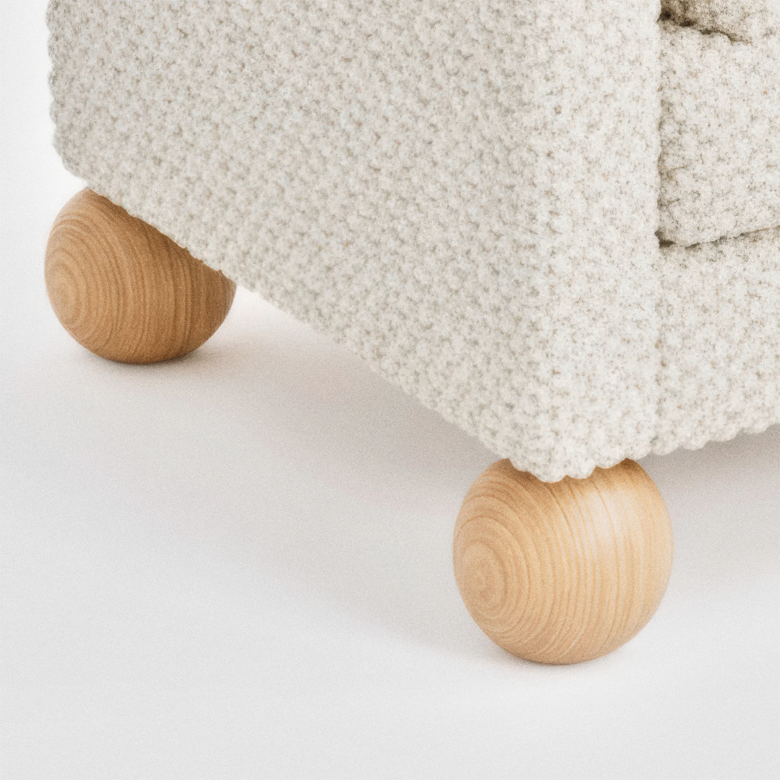 Белый диван с текстурной обивкой и ножками из светлого дерева.