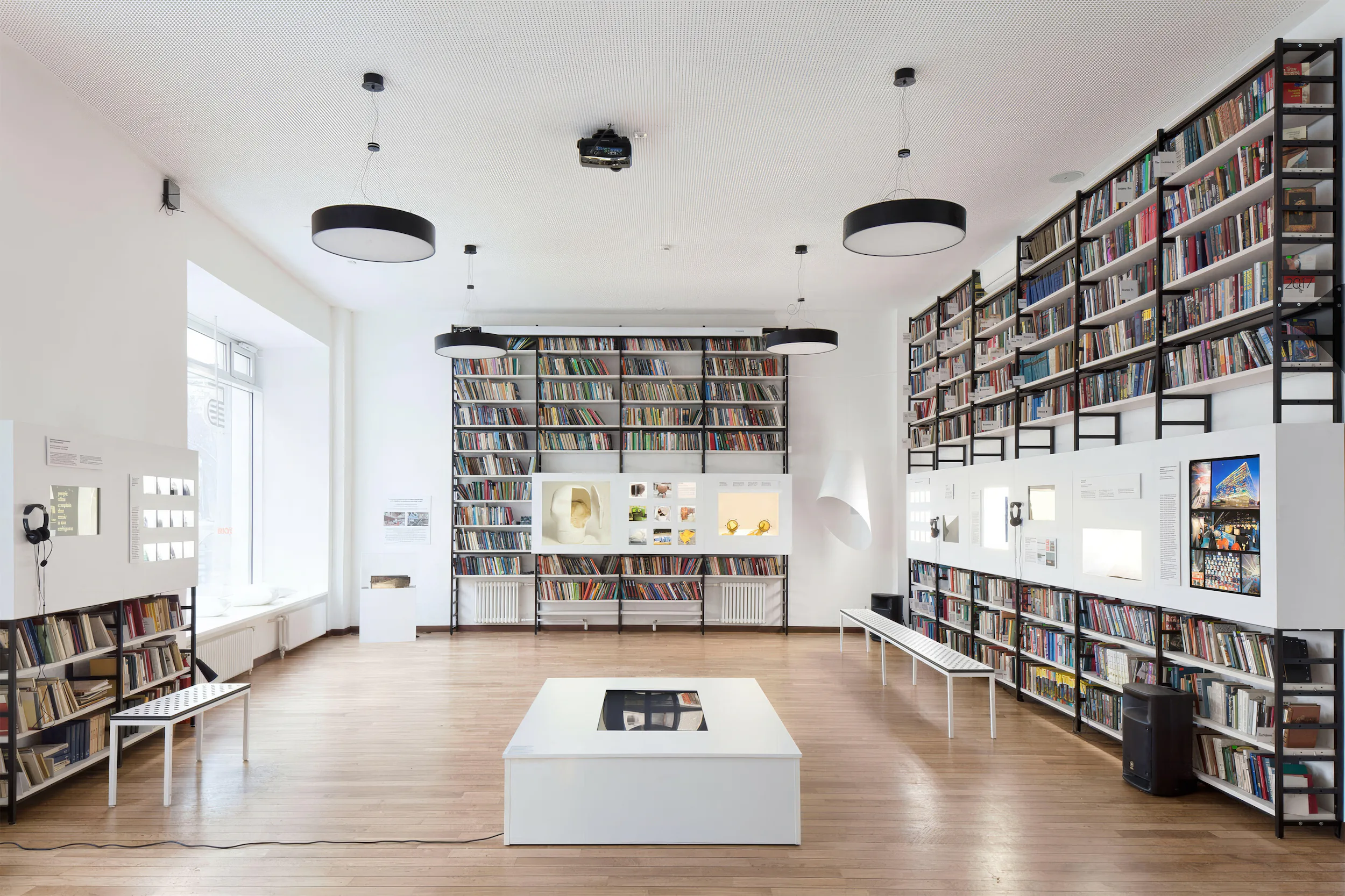 Комната с белым кофейным столиком и стеной, заставленной книгами.