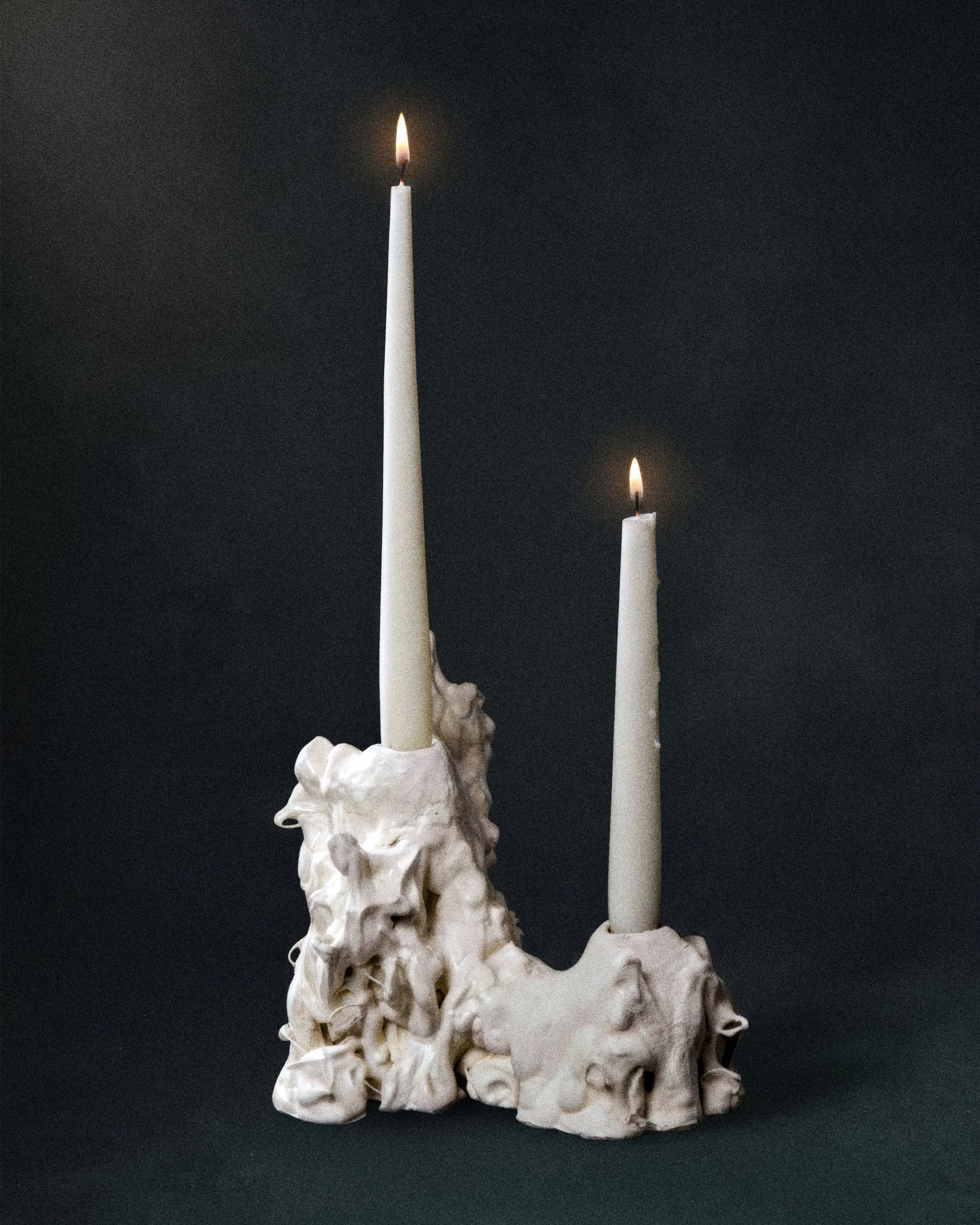 Белый подсвечник с двумя зажжёнными свечами на чёрном фоне.