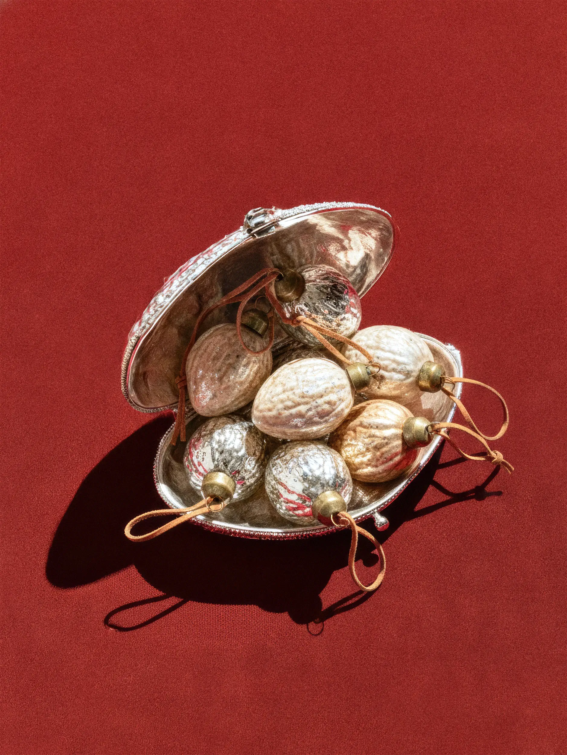 Четыре круглых украшения с золотым и серебряным орнаментом в небольшой открытой серебряной коробке.