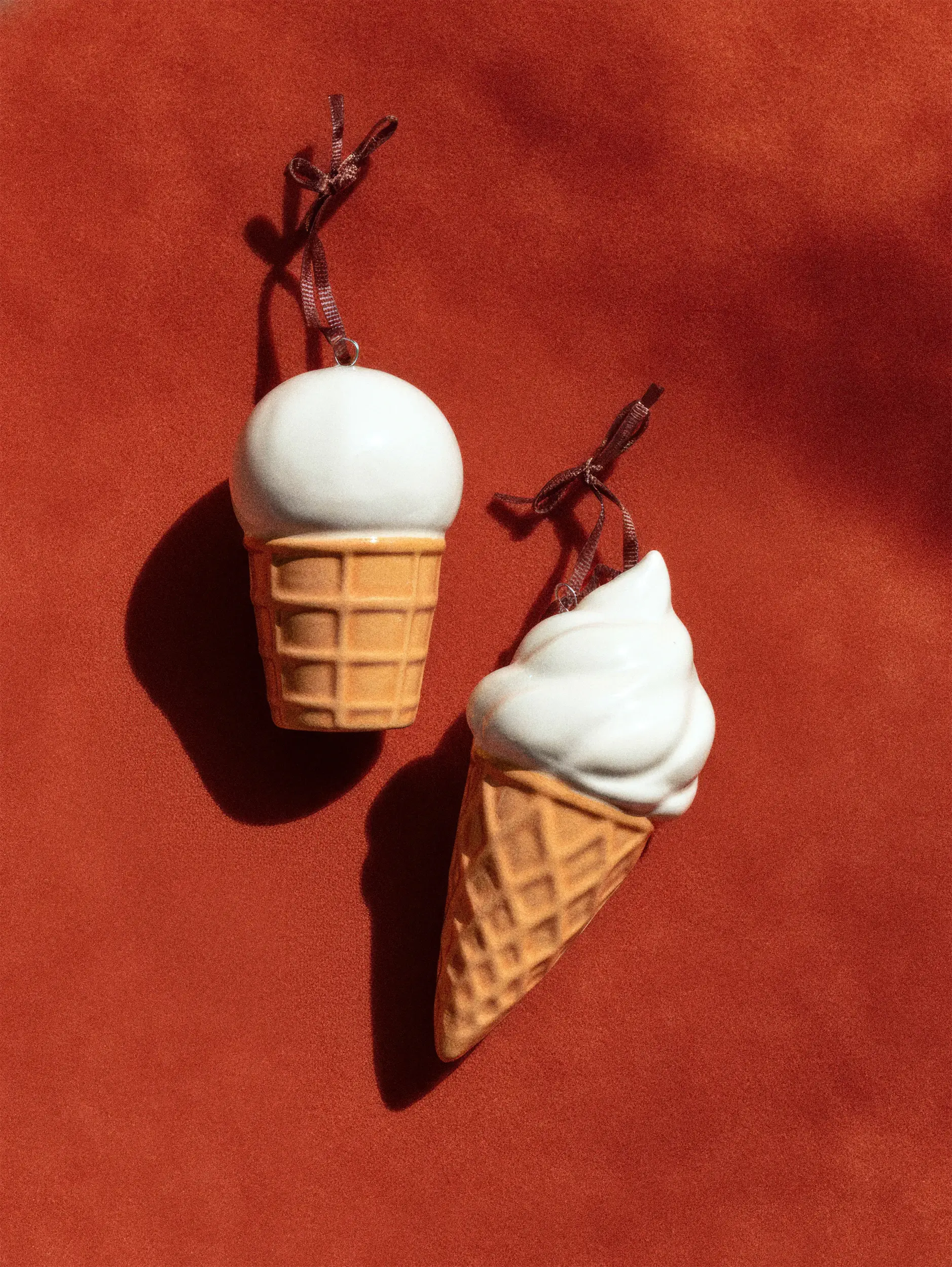 Два брелока в форме мороженого в вафельном рожке на красном фоне.