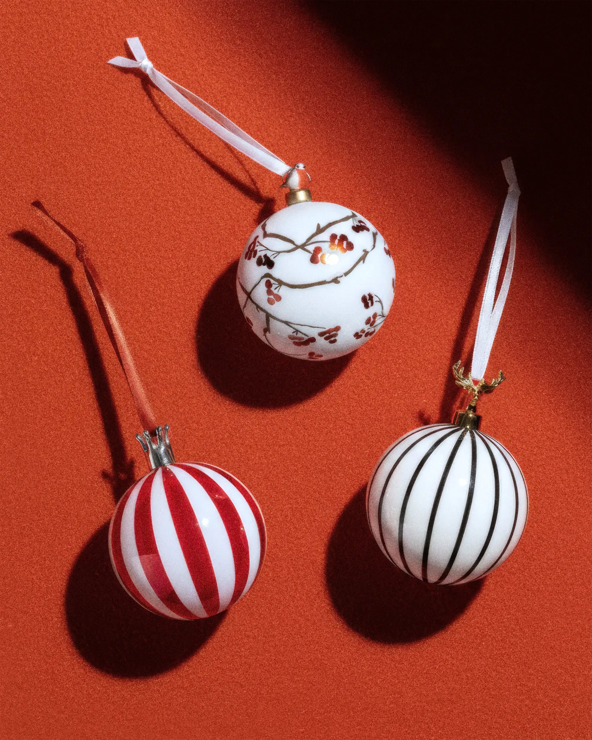 Рождественские украшения в красно-белую полоску с лентами на красном фоне.