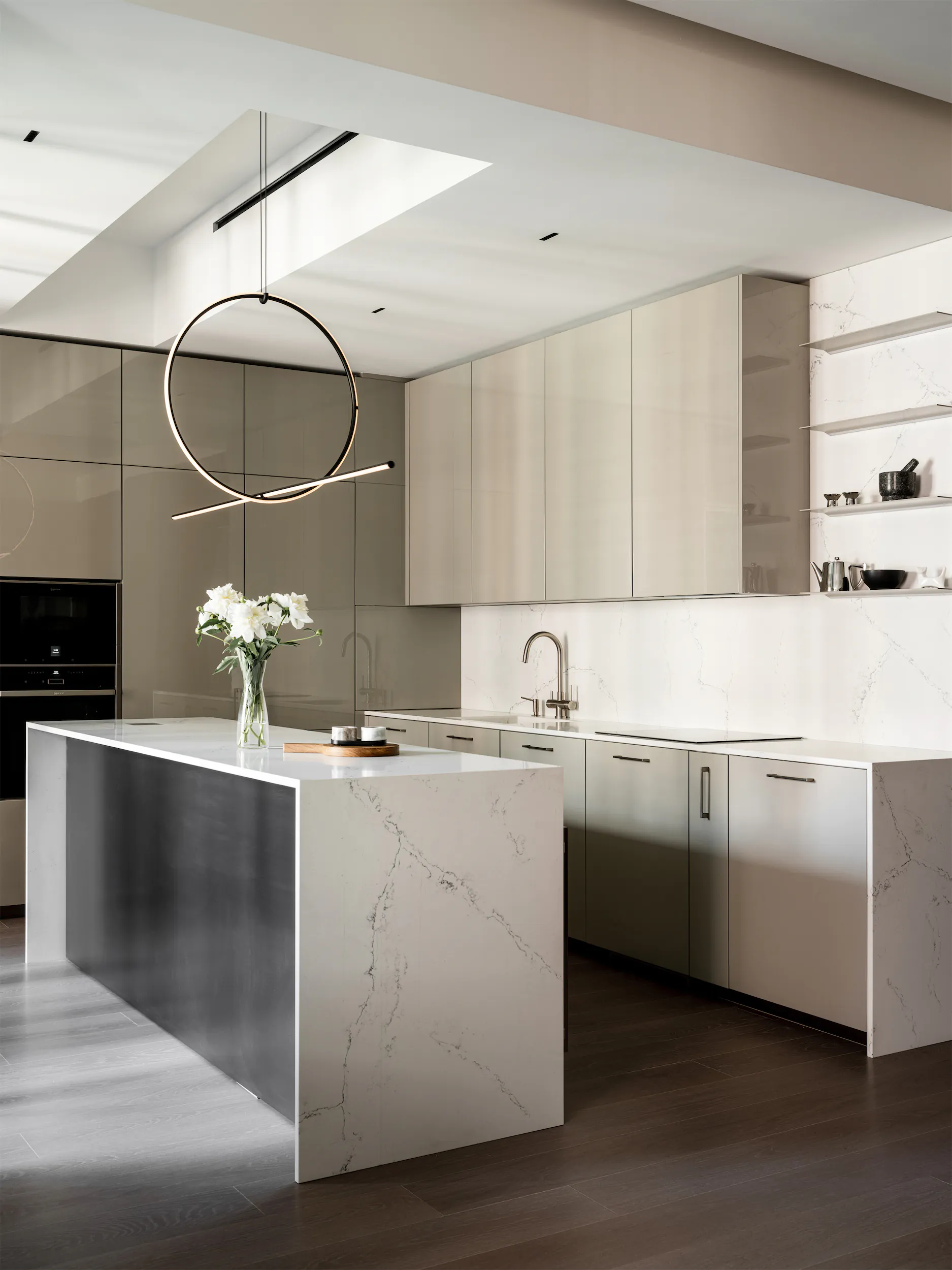 Современная кухня с белым мраморным островом и минималистичным подвесным светильником.