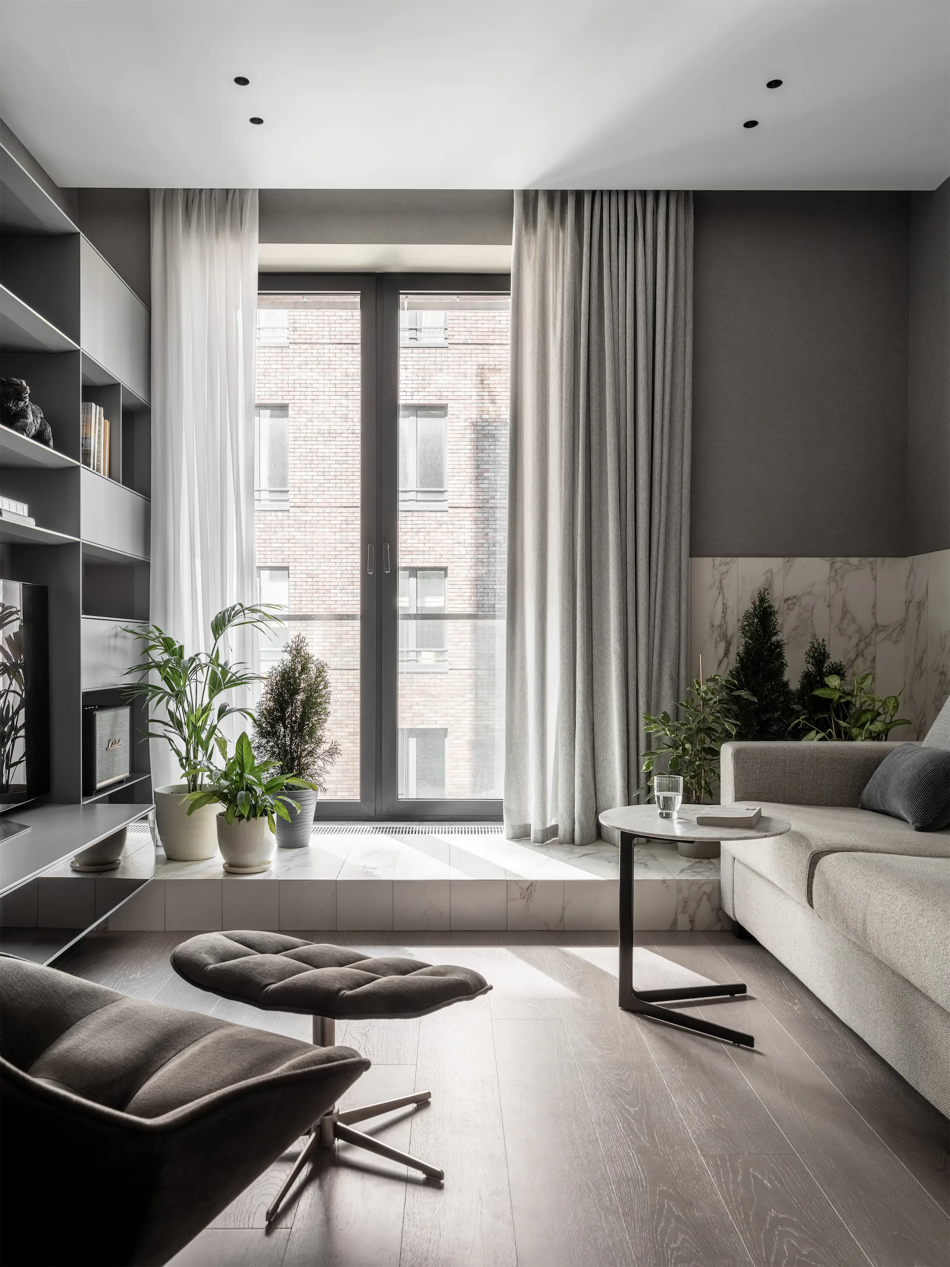 Современная гостиная с диваном, кофейным столиком и окном с видом на здание.