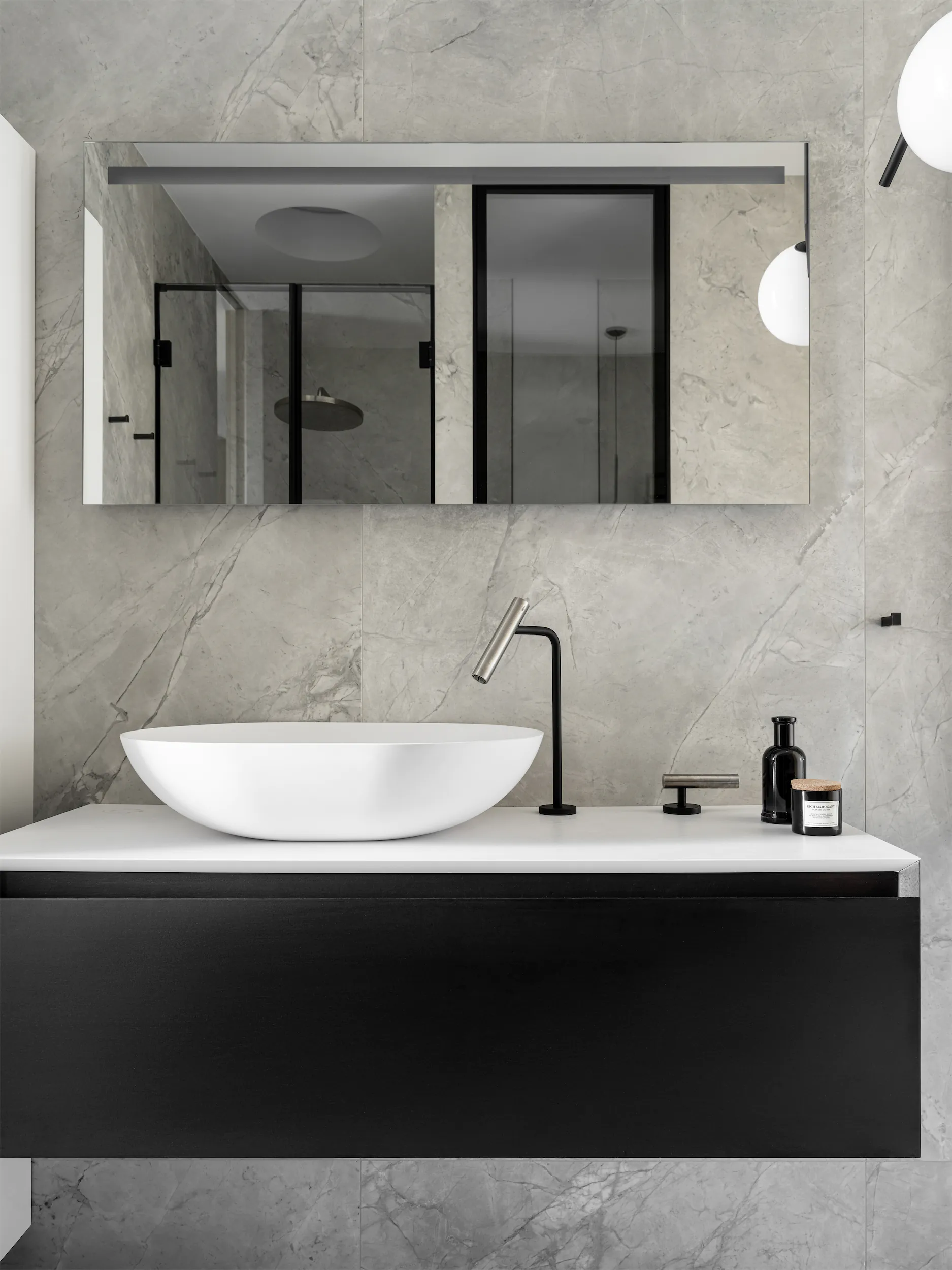 Мраморная стена с раковиной. Чаша белая, смеситель чёрный, зеркало прямоугольное.