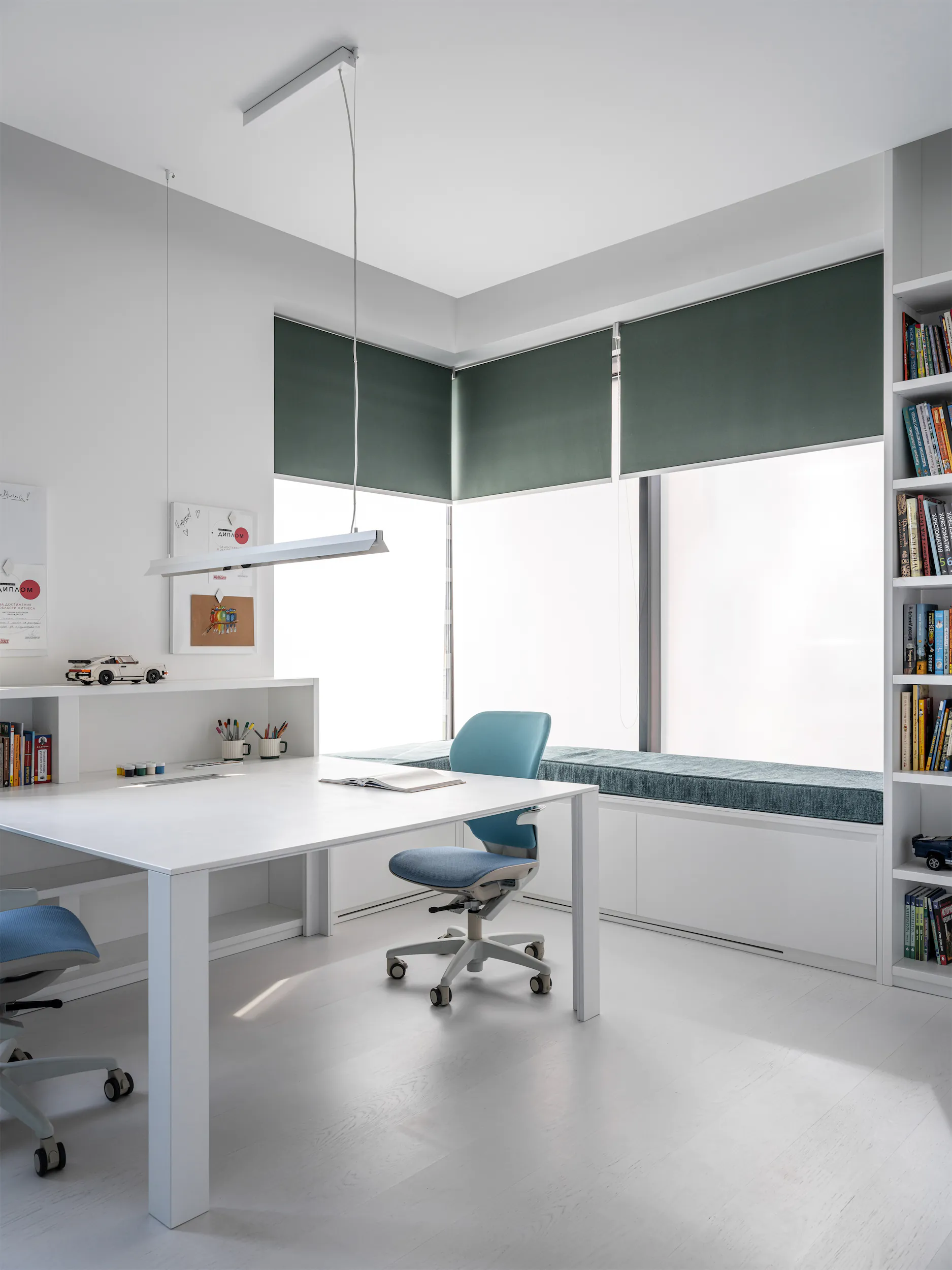 Современный рабочий кабинет с белым столом, синим креслом и встроенными полками.