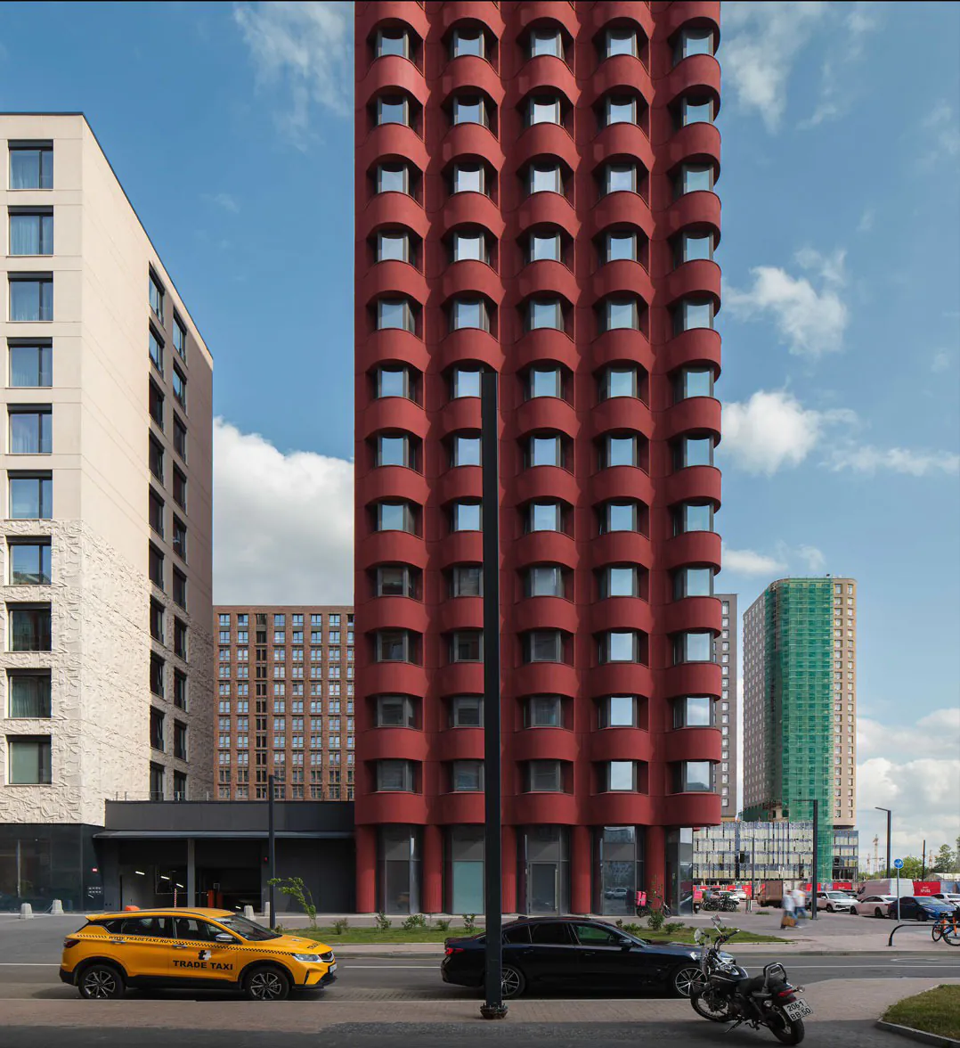 Высокое красное здание с округлыми окнами и выразительным дизайном.