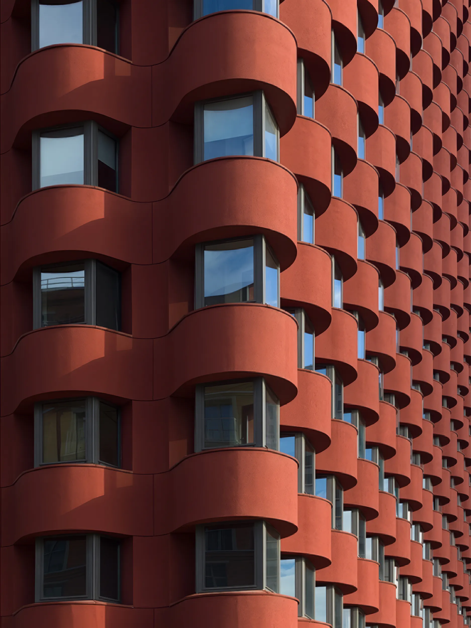 Высокое красное здание с множеством окон и балконов. Оригинальная архитектура.